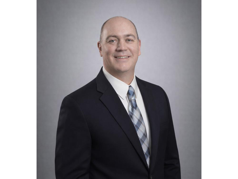Mark Rameker wearing suit and tie smiles for camera