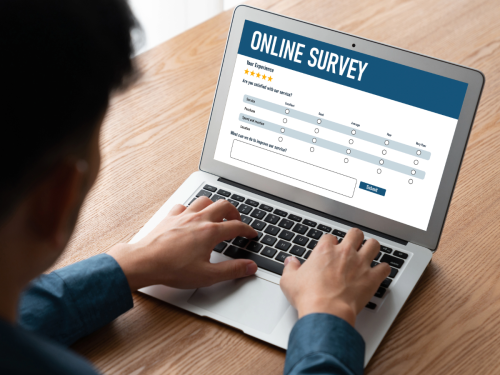 laptop screen with words online survey and multiple choice questions with student typing on keyboard