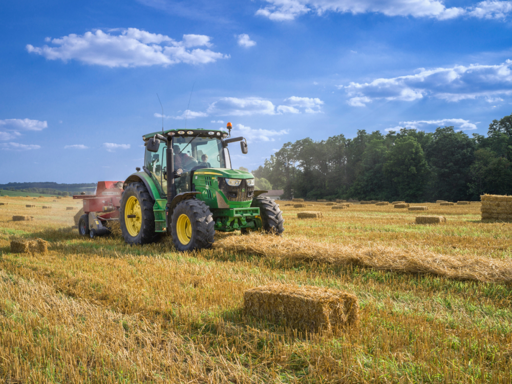 Tractor in a hay field next to a bale of hay