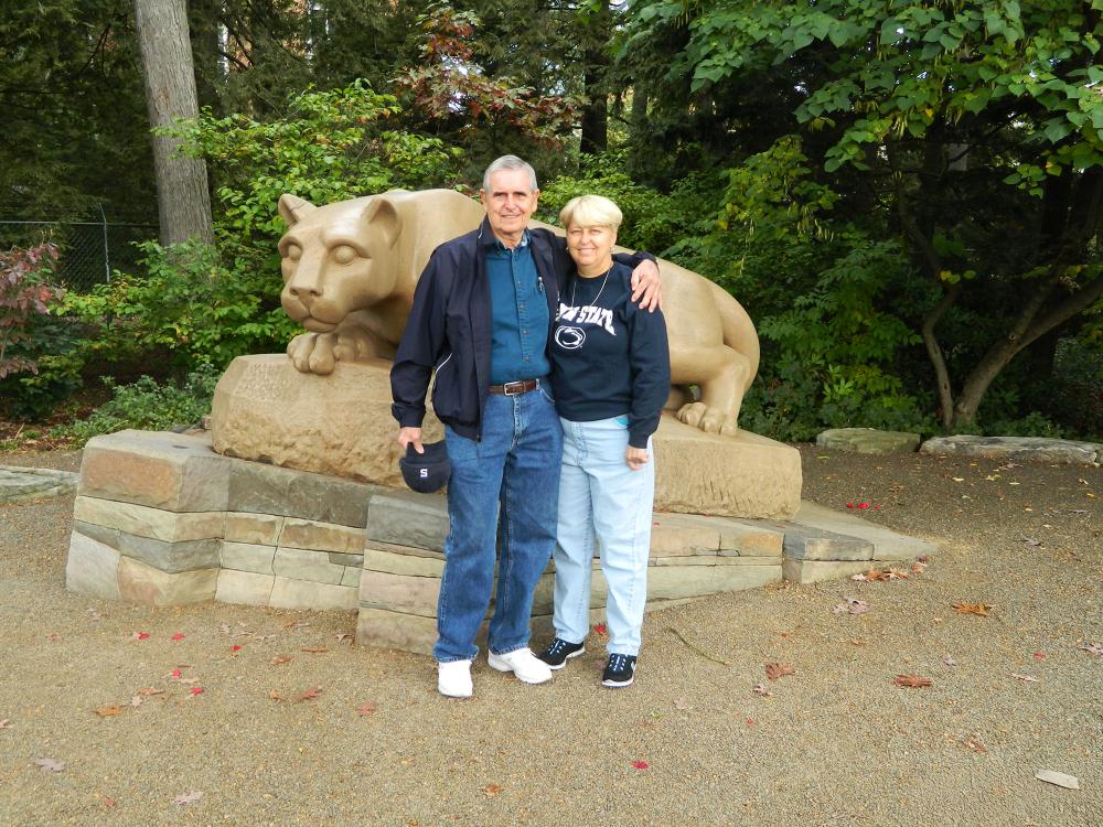 a man and a woman stand in front of the nittany lion shrine statue