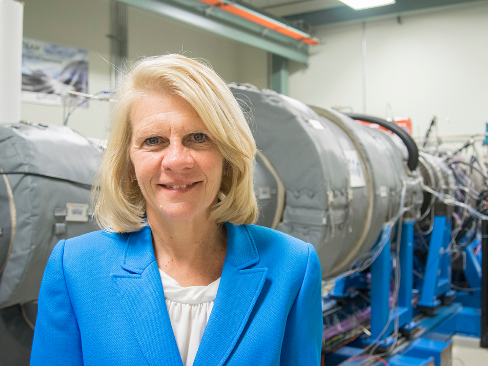 Karen Thole pictured in the Steady Thermal Aero Research Turbine Lab at Penn State, with a gas turbine engine in the background