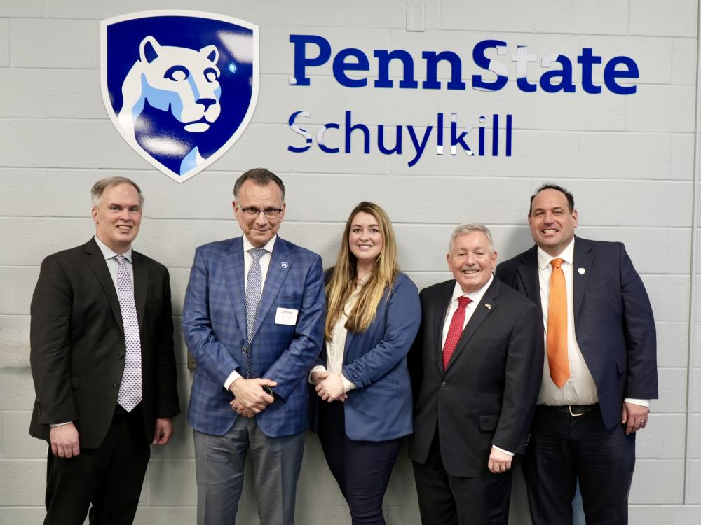 Five people stand for a photo in front of a sign that says Penn State Schuylkill