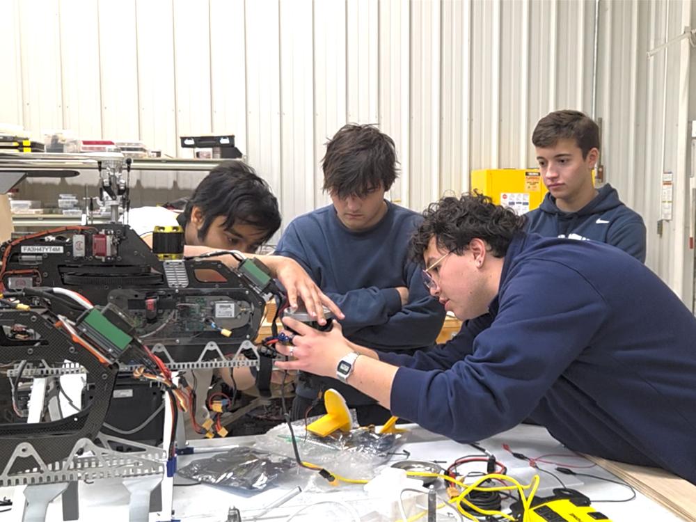Four people install a sensor on an unmanned aerial vehicle prototype. 
