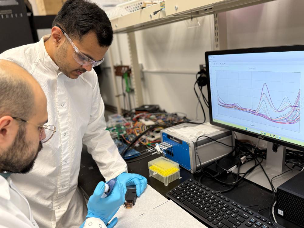 Two researchers in front of a computer, injecting a substance onto a sensory ship.