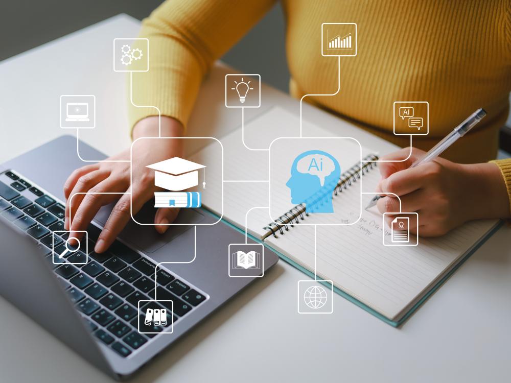 Closeup of a persons hands typing on a laptop and holding a pen