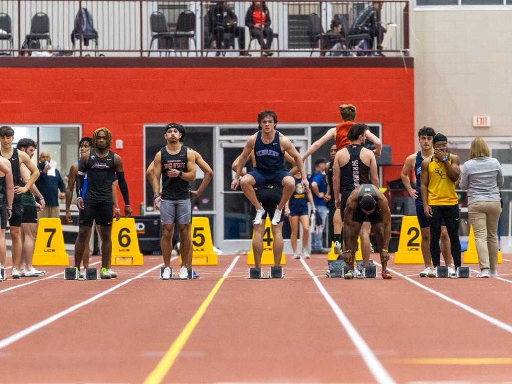 Penn State Behrend spinter Carter Tobin jumps at the starting line as other runners stretch.