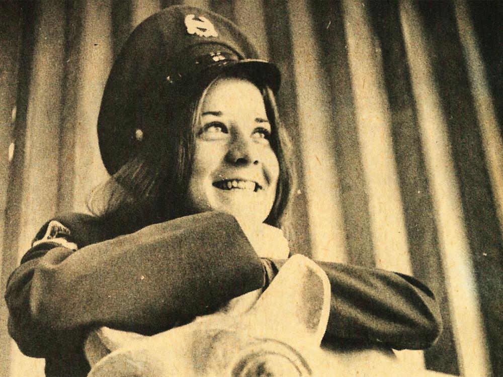 An newspaper photograph from 1972 of Amy Fowkes, wearing a military hat and leaning on a Nittany Lion statue.