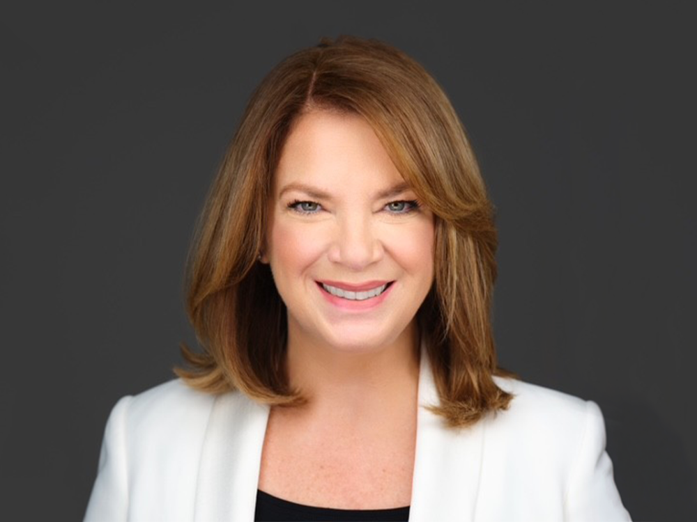 Gretchen Watkins smiling in front of dark grey background.