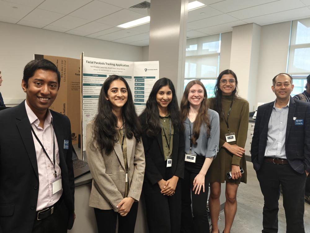 A group of six people stand in front of an academic poster