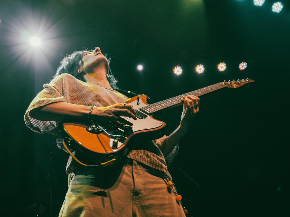 Leah Wellbaum plays the guitar while looking upward.