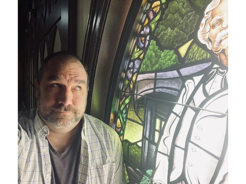 Matthew Seybold looking upward at a stained glass window of Mark Twain