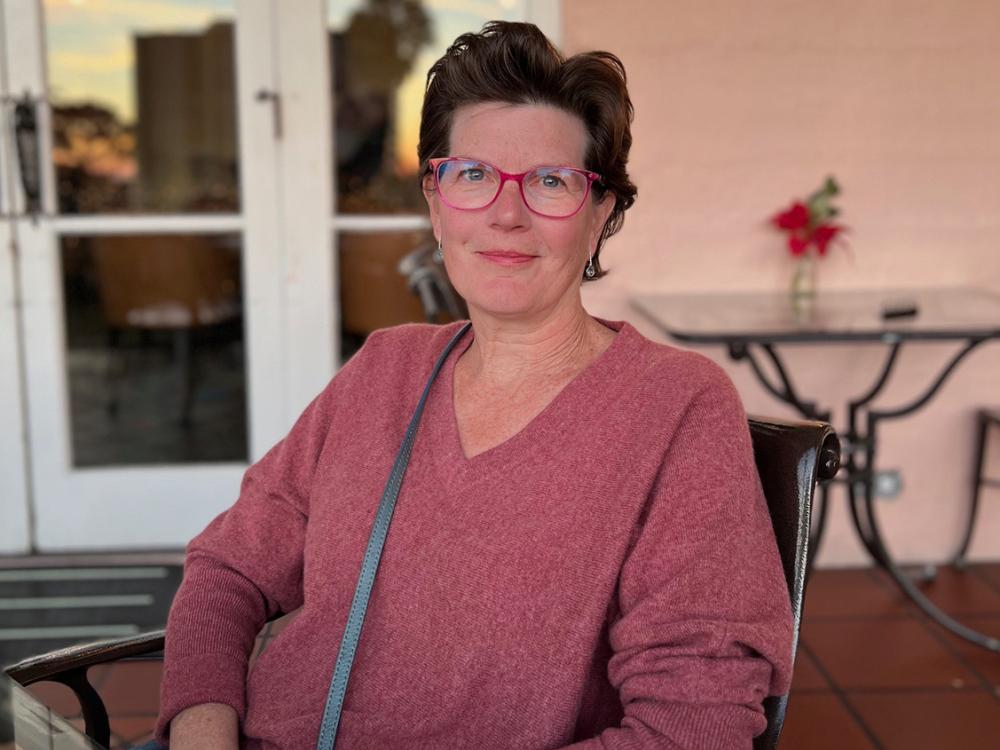 Melissa Daniels Foster smiling and sitting in a chair on a patio