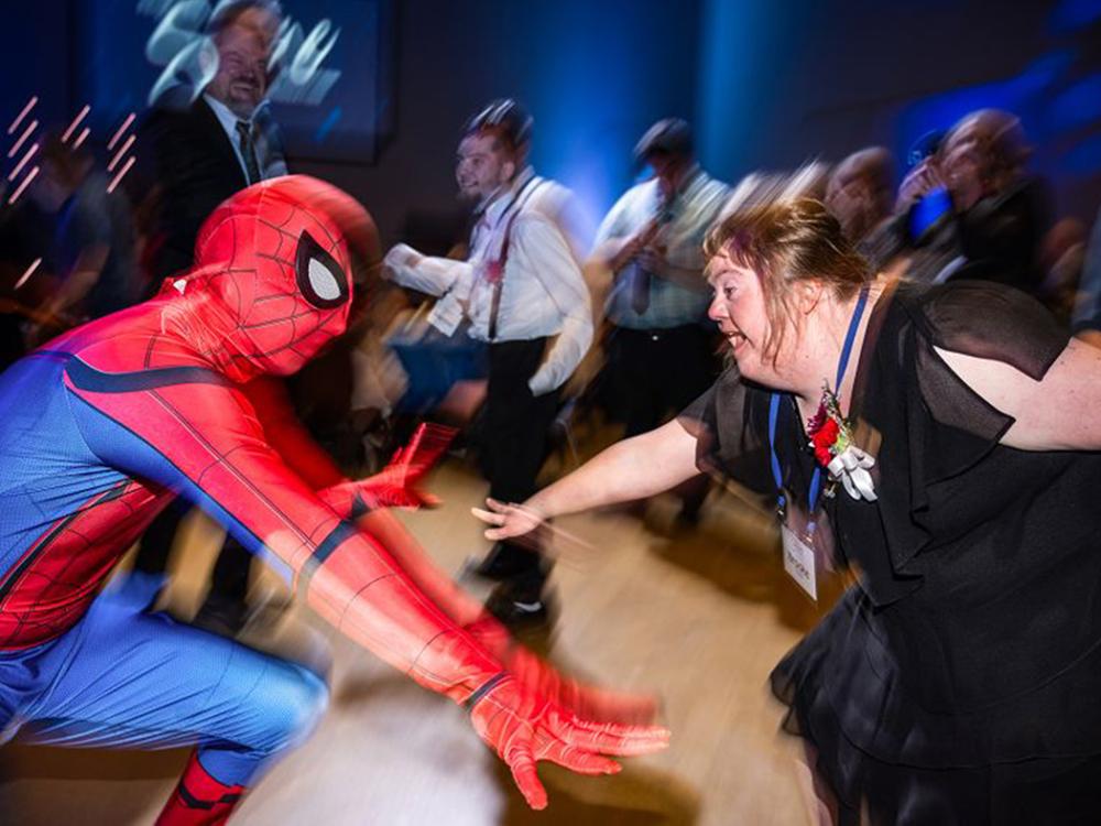 Someone dressed as Spider-Man dances with a woman in a black dress