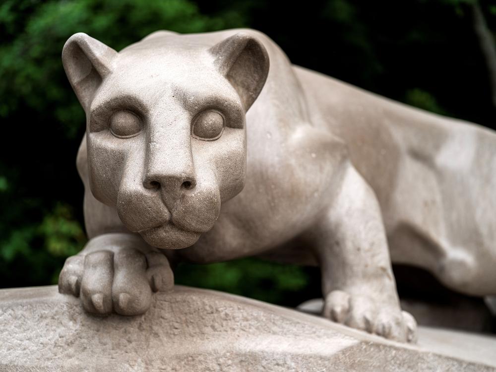 A statue of a Pennsylvania mountain lion crouched on a rock outcropping