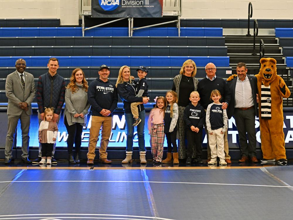 A group of family members and supporters stand together on a gym floor at Penn State Altoona, joined by the Nittany Lion mascot.