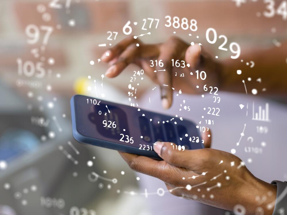 Close-up of a person holding and tapping on a smartphone, with floating numbers, graphs, and data visualizations overlaid around the device.