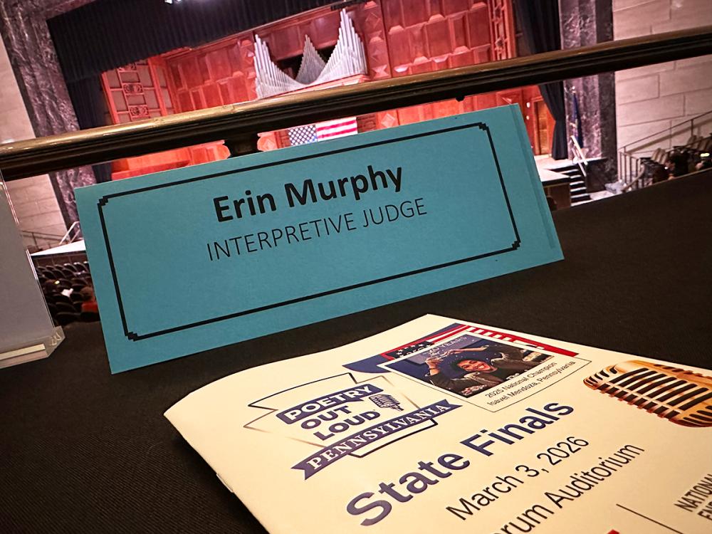 A name placard reading Erin Murphy, Interpretive Judge sits on a desk overlooking the stage at the Poetry Out Loud Pennsylvania State Finals.