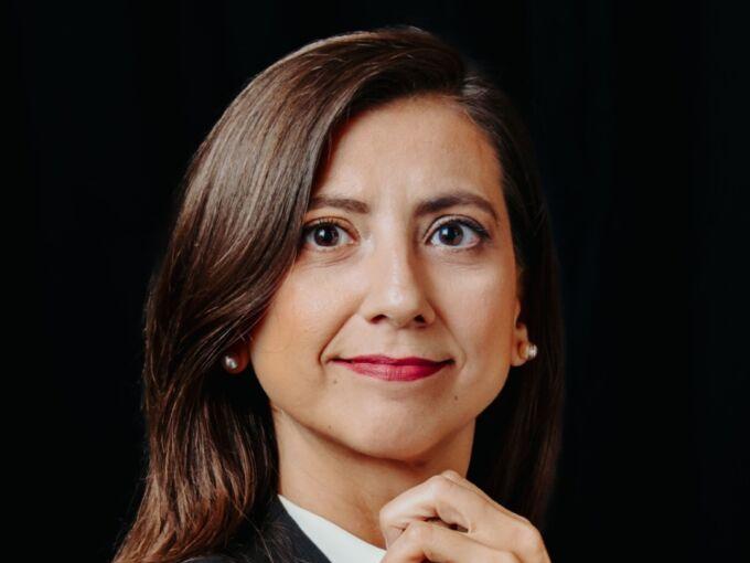 Headshot of woman with long dark hair, holding a conductor's baton