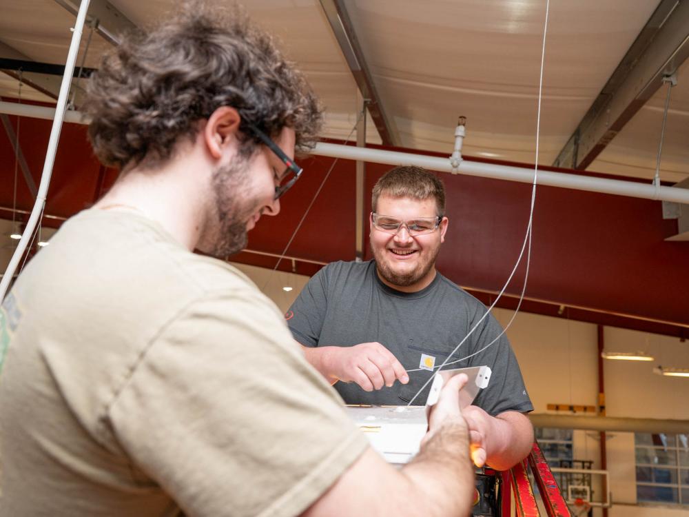 Two students work with electrical equipment between them
