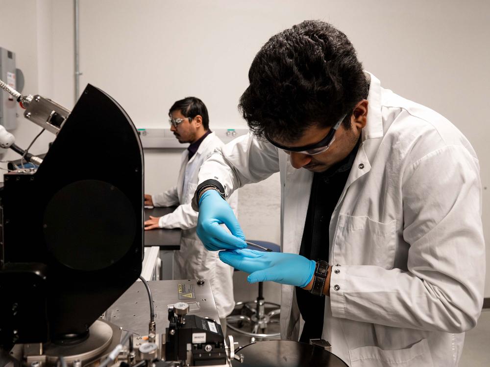 Anirban Chowdhury and Dipanjan Sen work in the lab, moving a thermal sensor into an imaging system.