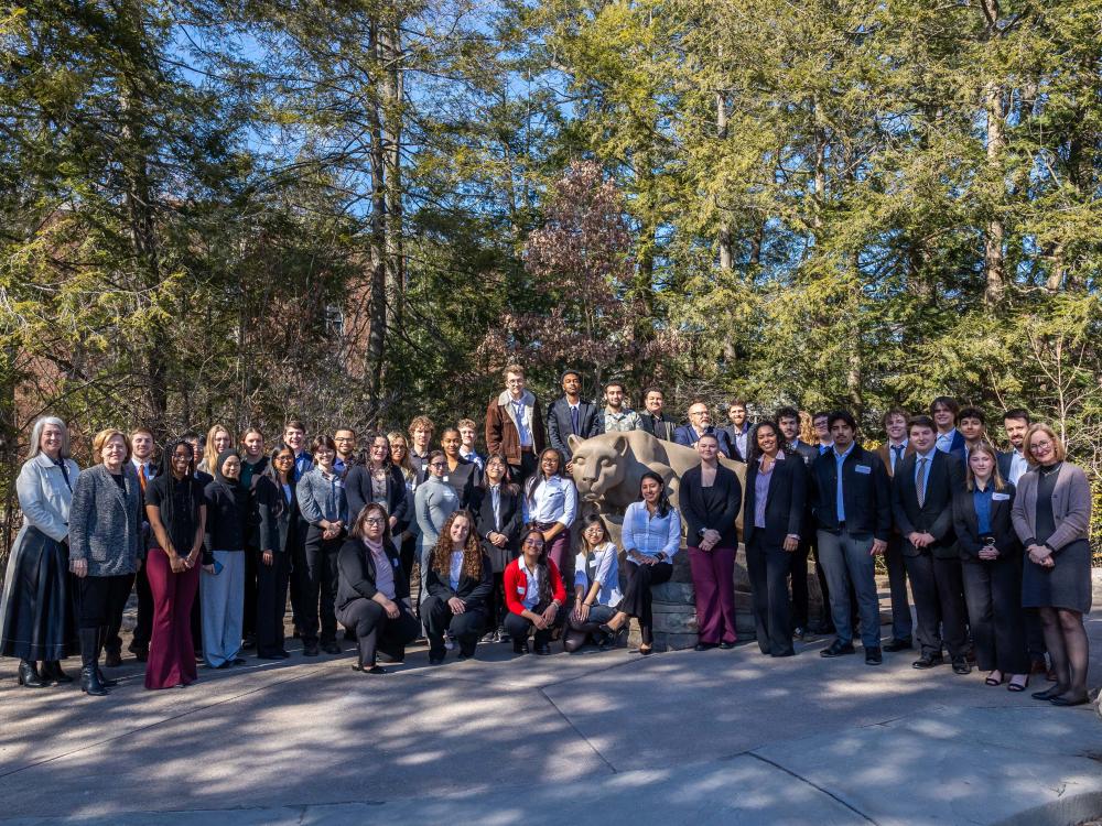 A group of people pose around the Nittany Lion Shrine.
