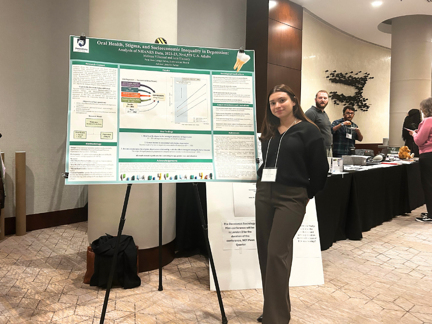A Penn State Lehigh Valley student standing next to a research poster