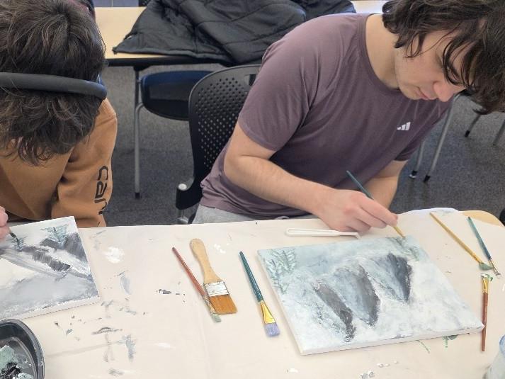 Two students looking down as they create artwork in a classroom