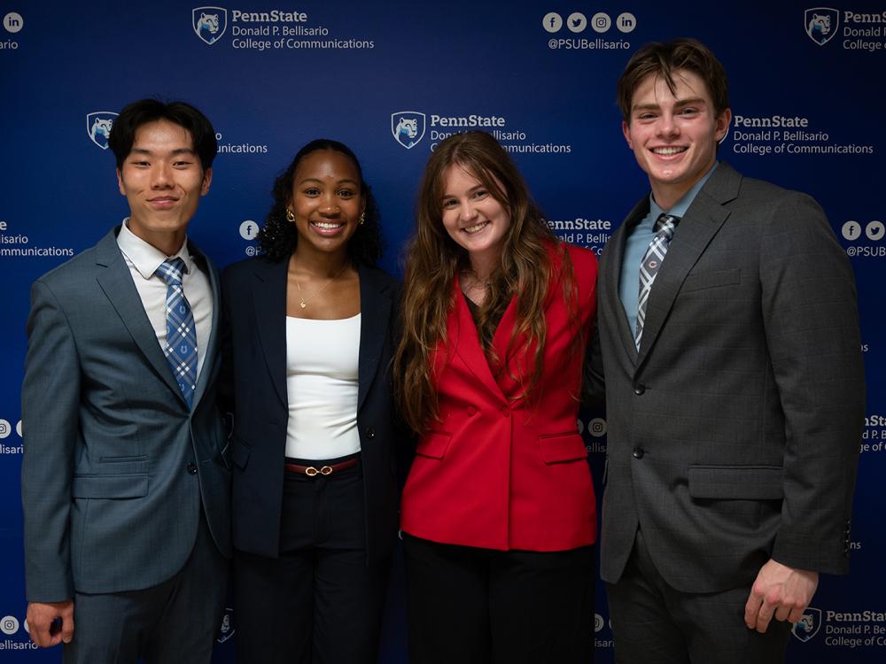 Four students arm in arm, in business attire