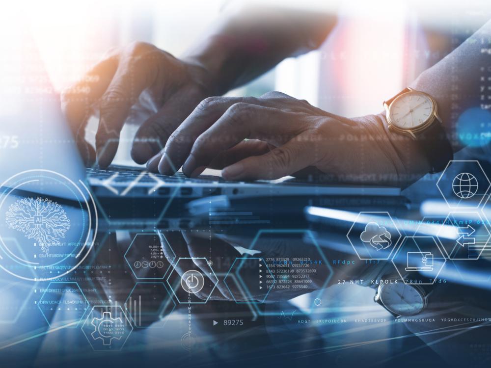 Hands typing on a laptop with computing graphics