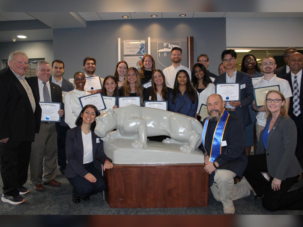 Newly inducted members of business honor societies and faculty pose with the Lion statue in Olmsted Building