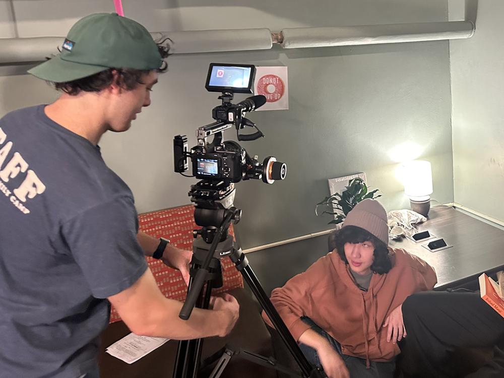 A man in a blue shirt adjusts a camera to shoot a film scene.