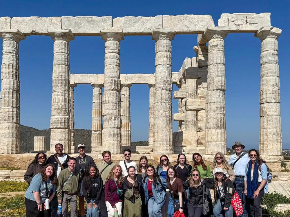 Students stand in a big group in front of the Sounion archaeological site in Greece.