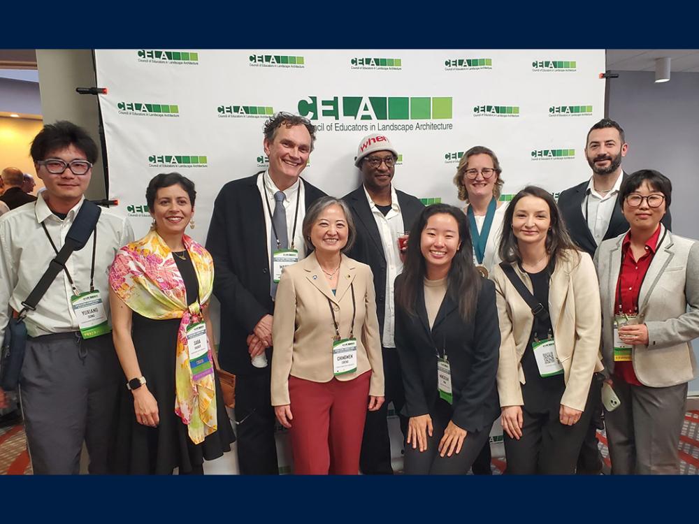 A group of people gathered in front of a green and white backdrop that reads "CELA."