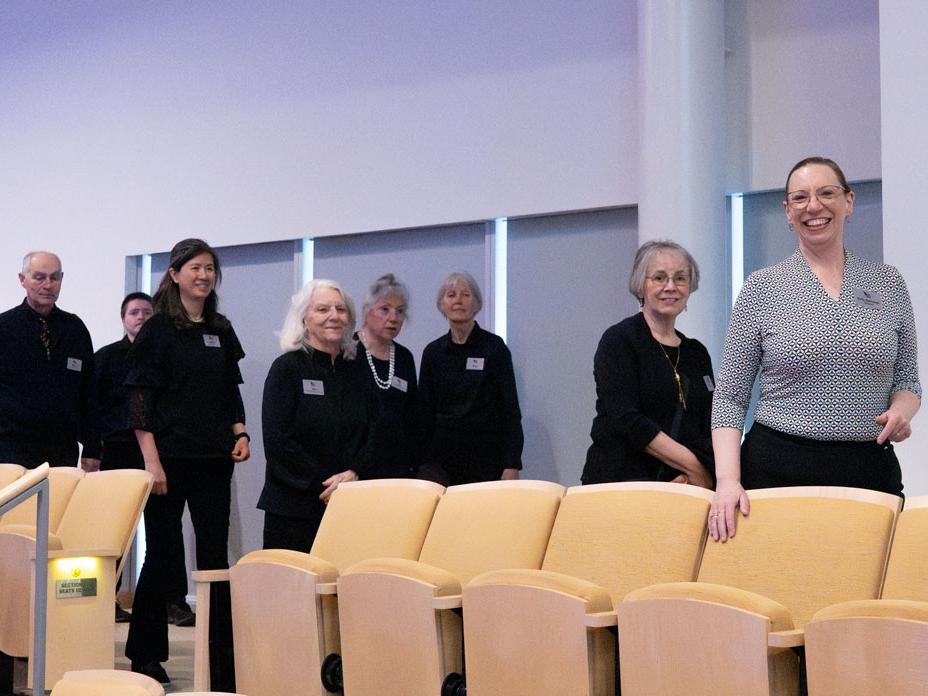A group of people stand behind a row of auditorium seats.