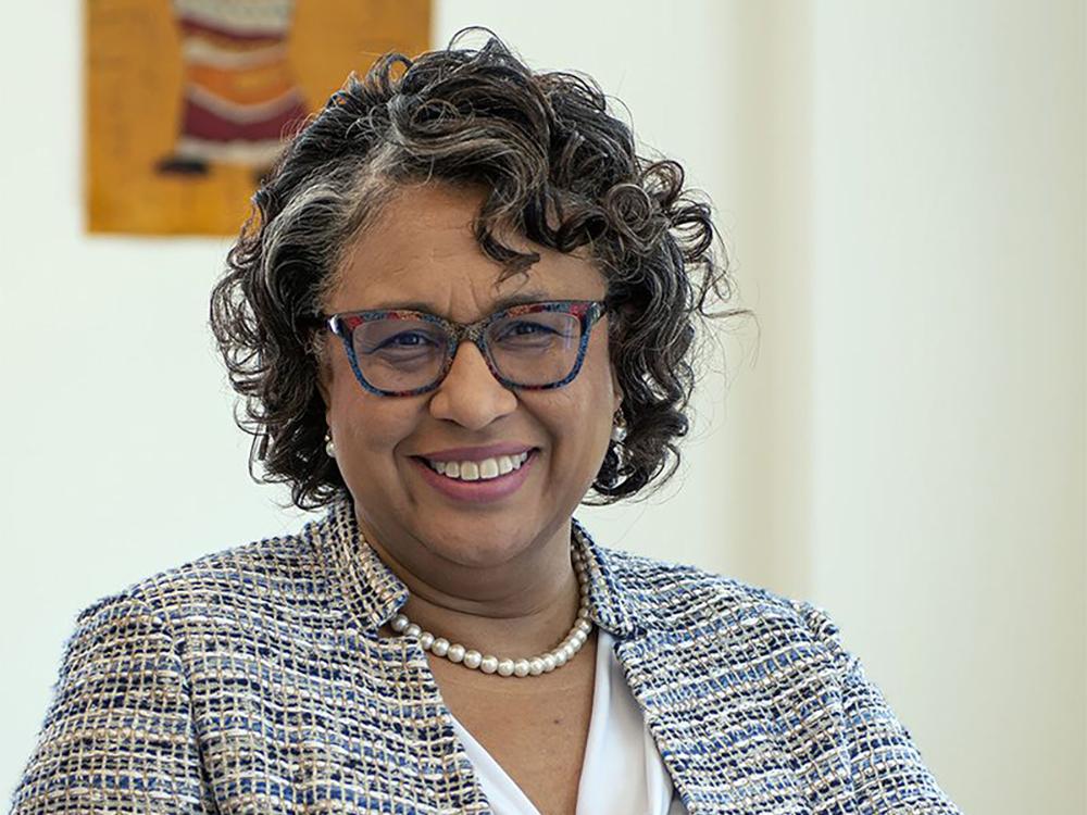 Woman with glasses wearing a suit and smiling for the camera.