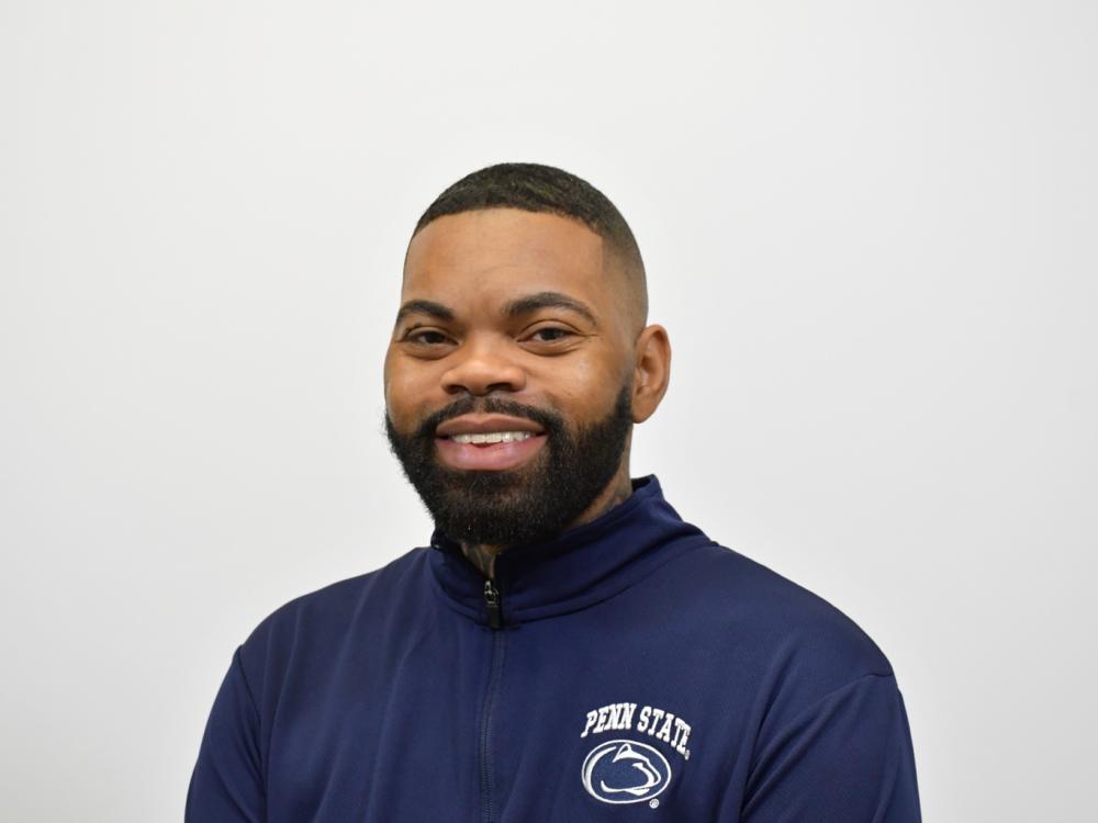 ML Brown, a Penn State College of Education doctoral candidate in special education, smiles in a headshot wearing a navy Penn State quarter-zip against a neutral background.