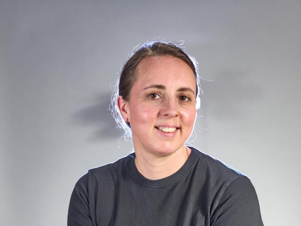 Woman in gray shirt with hair pulled back