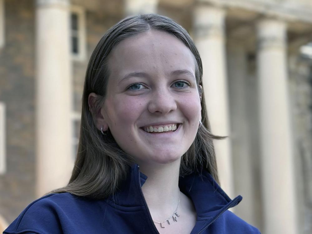 Maddie Shanafelt, a Penn State College of Education student, smiles in a headshot wearing a navy jacket in front of campus columns.