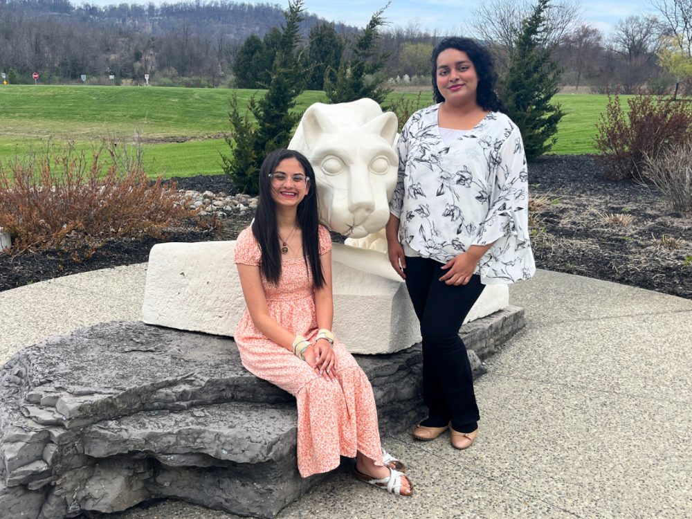 two female students sit next to the lion shrine on the Penn State Lehigh Valley campus