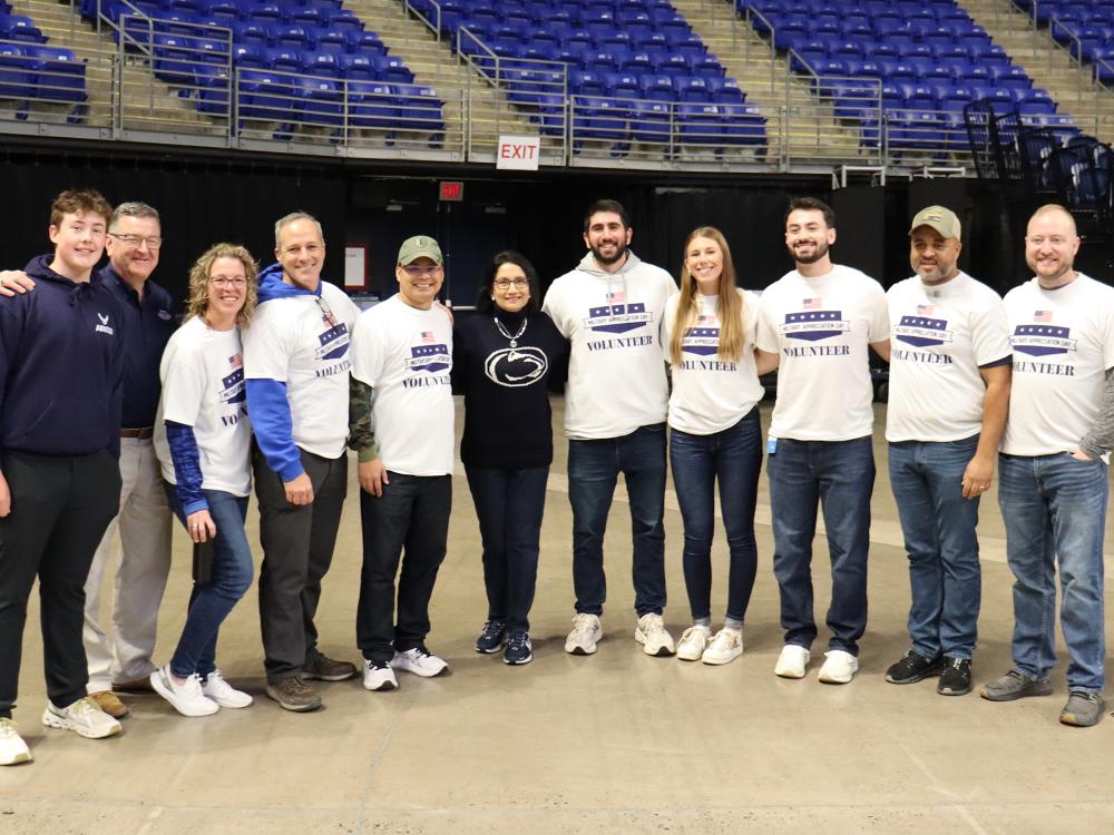 12 people stand in a line in an empty arena.