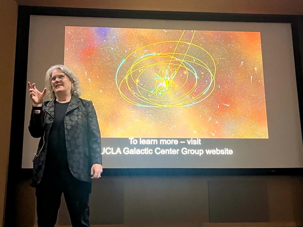 Andrea Ghez stands in front of projected screen