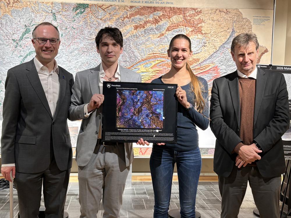 Four people pose with a colorful image