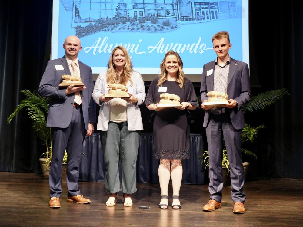 Four people holding small Nittany Lion statues