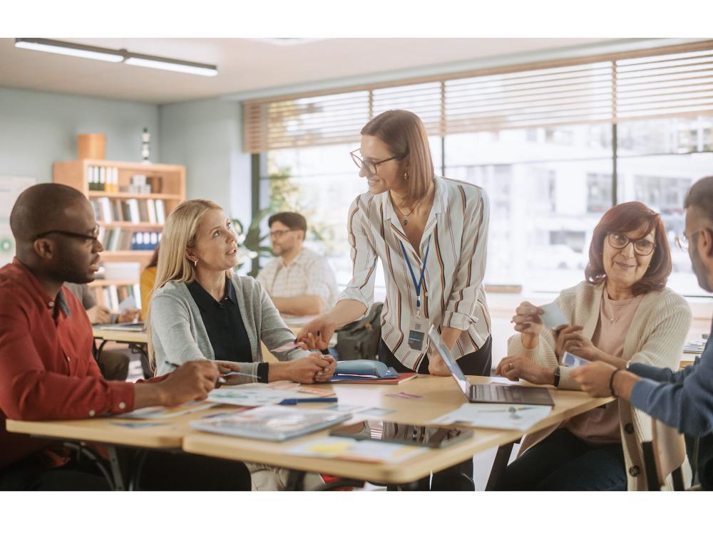 Group of educators engaged in a discussion around a table in a classroom setting.