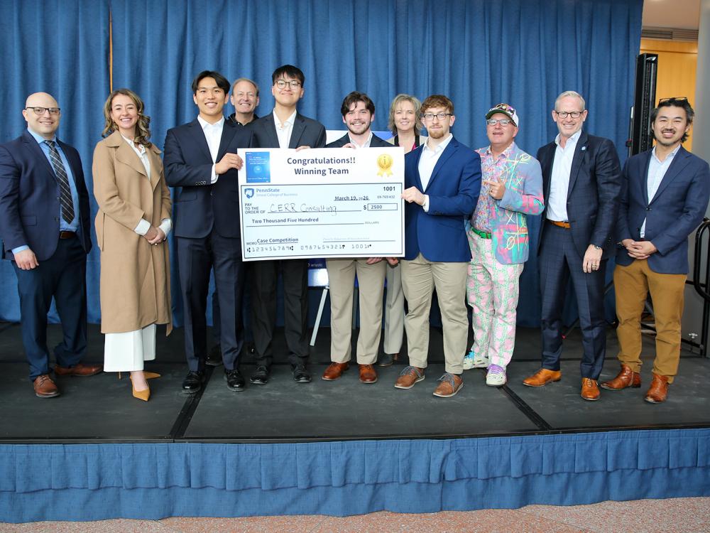 Four Smeal students hold a faux first-place check for $2,500, surrounded by adult judges of the Ives AI Innovation Case Competition