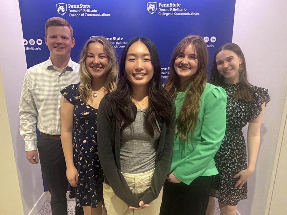 Five smiling students, one man and four women