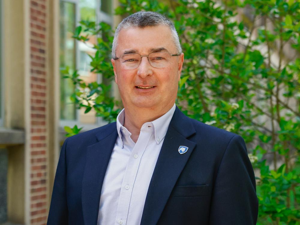 A head shot of a male employee outside a campus building.