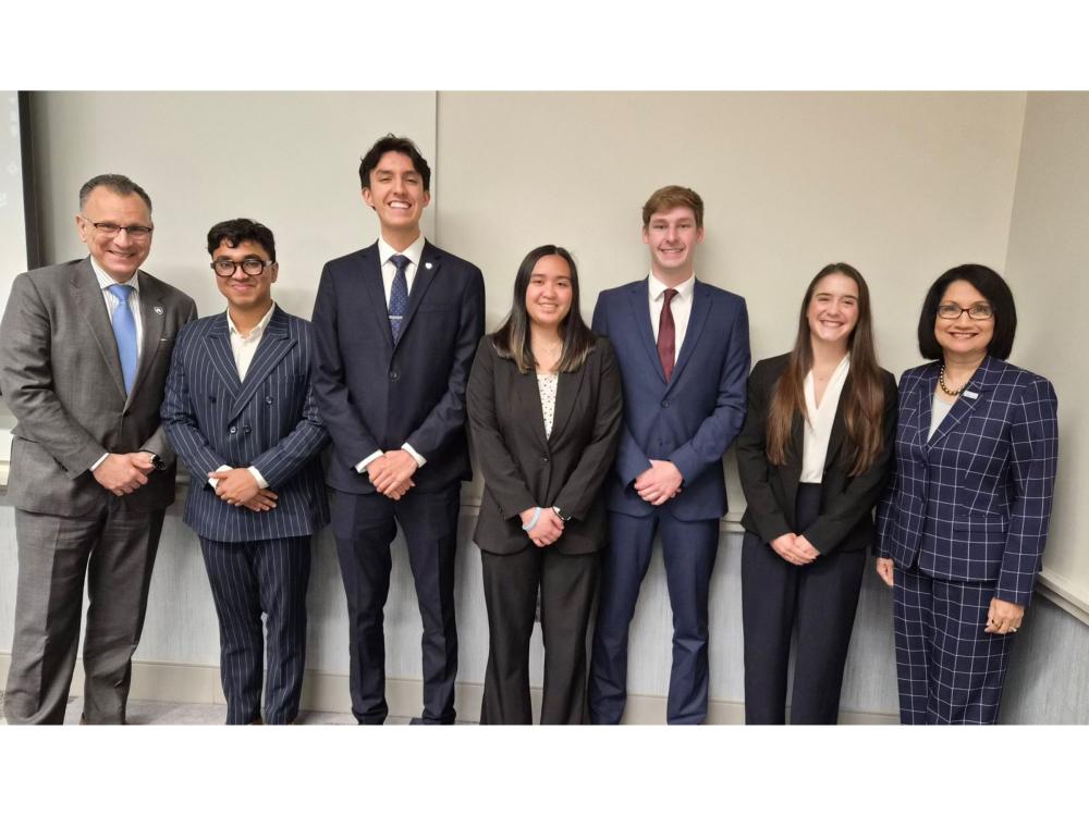 Seven individuals wearing suits pose for the camera