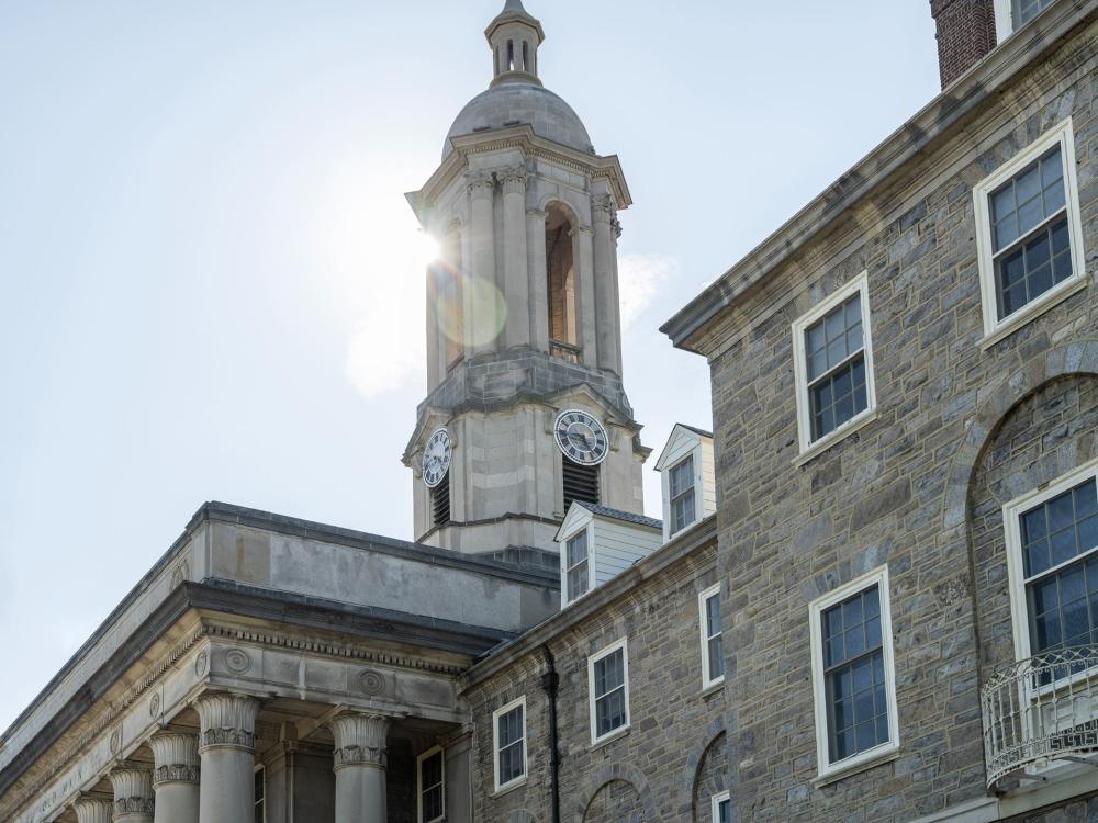 A sunny photograph of the stone bell tower of Old Main against a blue sky.