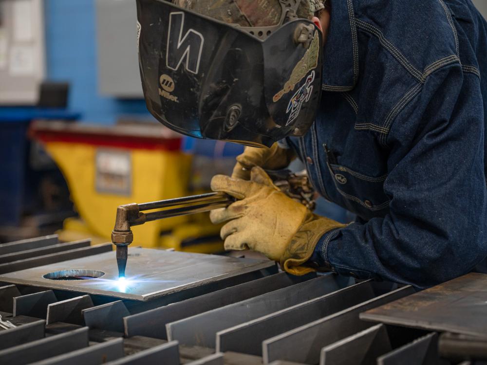 A person uses a piece of welding equipment on some metal